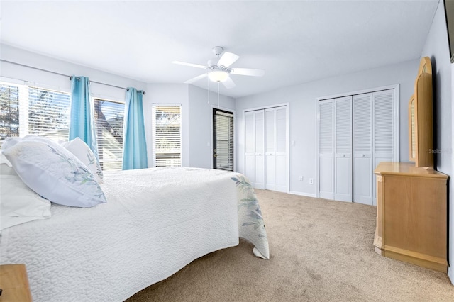 bedroom featuring ceiling fan, light carpet, and two closets