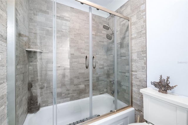 bathroom with bath / shower combo with glass door and toilet