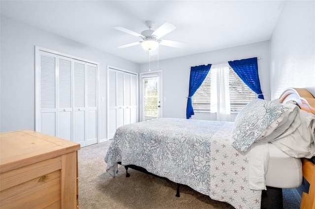 carpeted bedroom with ceiling fan and multiple closets