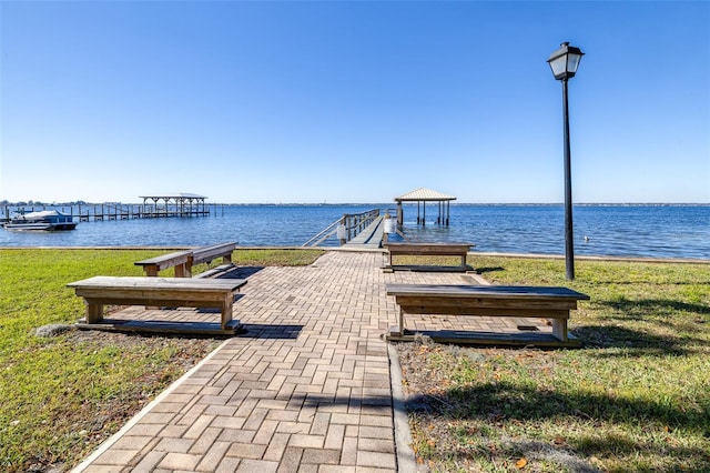 view of dock with a lawn and a water view