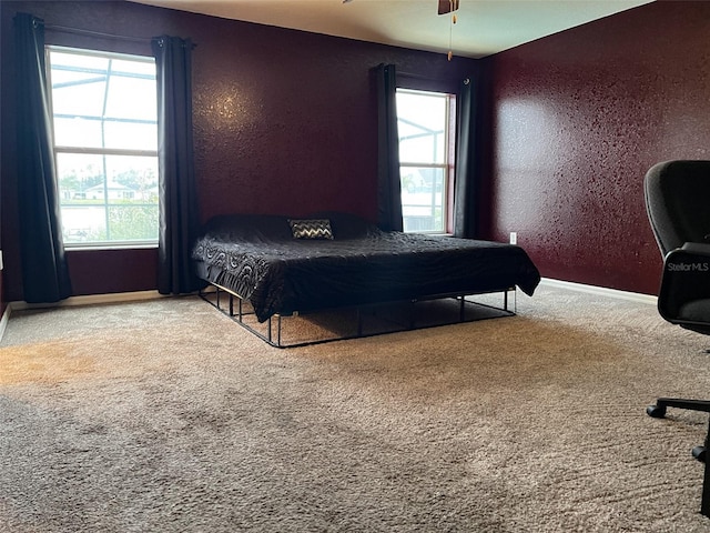 carpeted bedroom with ceiling fan and multiple windows