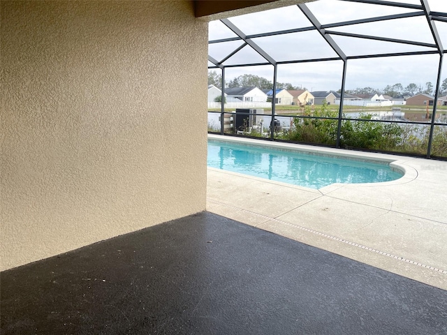 view of swimming pool with a water view, glass enclosure, and a patio