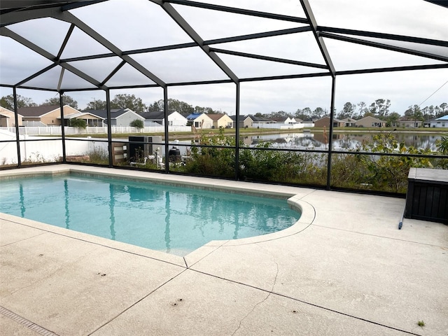 view of pool with a patio area, glass enclosure, and a water view