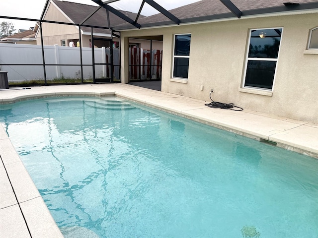 view of swimming pool featuring fence, a fenced in pool, a lanai, and a patio area