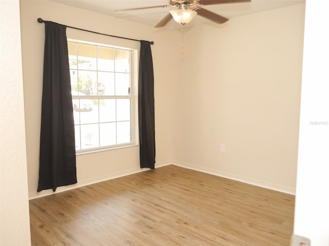 unfurnished room with a ceiling fan, baseboards, and light wood-type flooring