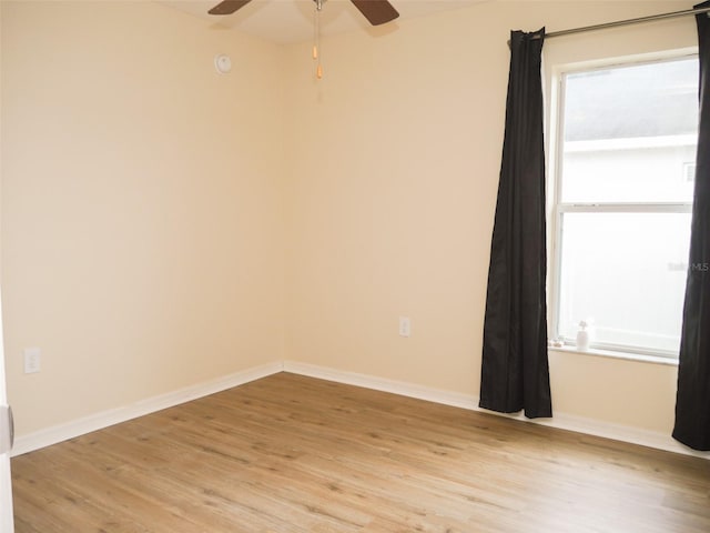 spare room with baseboards, a ceiling fan, and light wood-style flooring