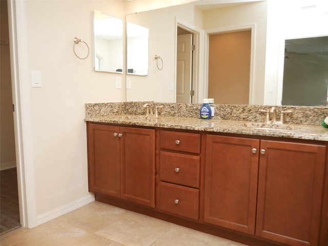 bathroom featuring a sink, baseboards, tile patterned flooring, and double vanity