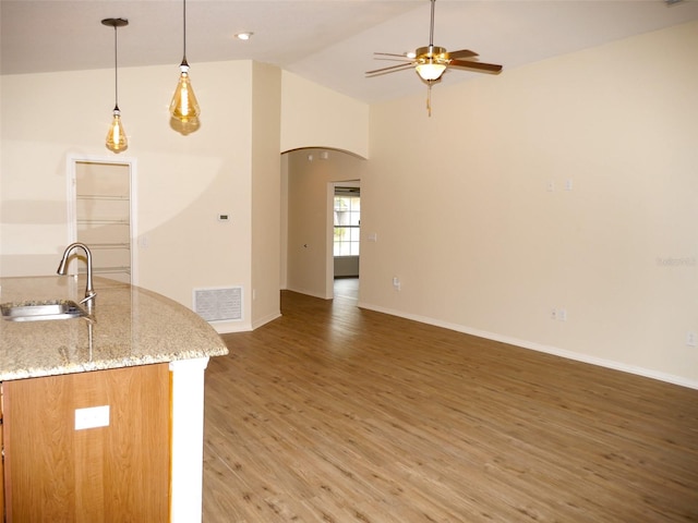 kitchen featuring ceiling fan, a sink, light wood-style floors, lofted ceiling, and visible vents