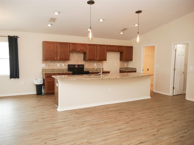 kitchen with visible vents, tasteful backsplash, a sink, and black range with electric stovetop
