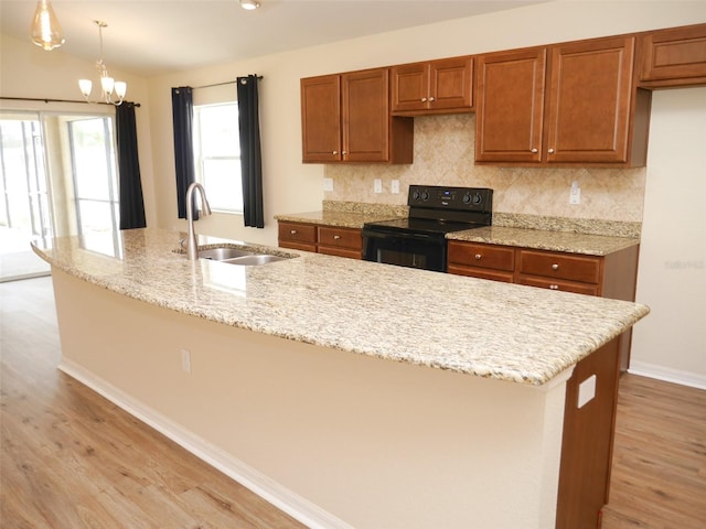 kitchen with a sink, light wood-style flooring, black electric range oven, and brown cabinets