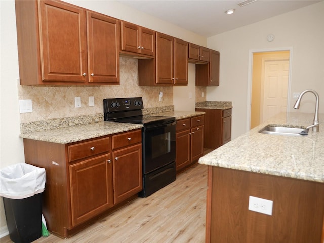 kitchen with decorative backsplash, light wood-type flooring, a sink, and black range with electric cooktop