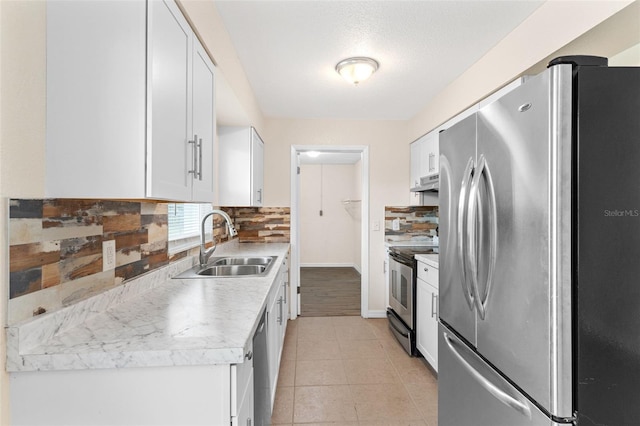 kitchen featuring white cabinets, sink, decorative backsplash, light tile patterned flooring, and stainless steel appliances