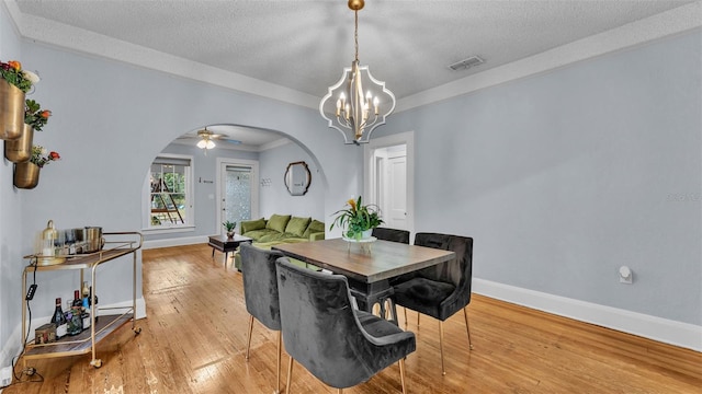 dining area with ceiling fan with notable chandelier, a textured ceiling, and light hardwood / wood-style flooring