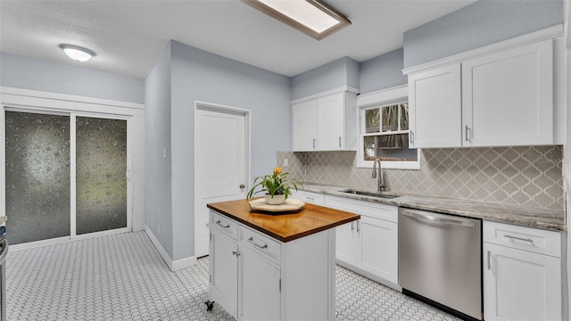 kitchen with dishwasher, white cabinets, sink, tasteful backsplash, and light stone counters