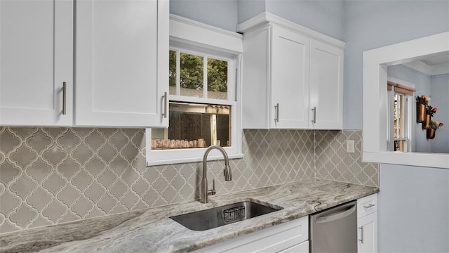 kitchen with stainless steel dishwasher, light stone countertops, white cabinetry, and sink