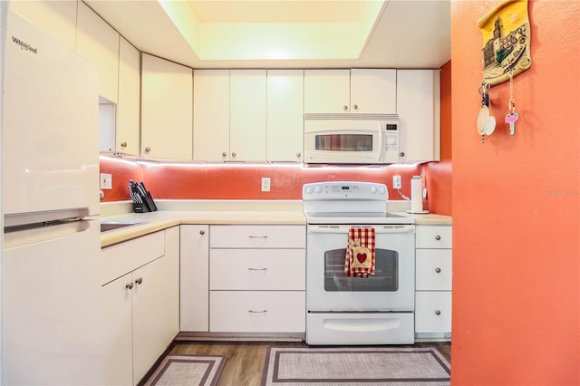 kitchen featuring white appliances, white cabinets, and dark hardwood / wood-style floors