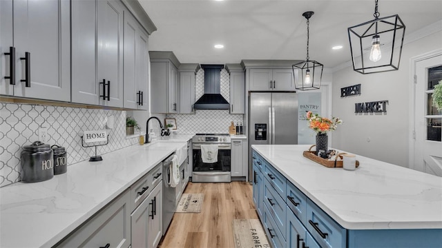 kitchen featuring hanging light fixtures, wall chimney exhaust hood, decorative backsplash, light wood-type flooring, and stainless steel appliances