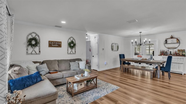 living room with crown molding, light hardwood / wood-style flooring, and a chandelier