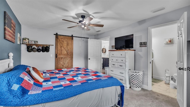 bedroom with a textured ceiling, a barn door, light colored carpet, and ceiling fan