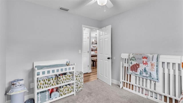 carpeted bedroom featuring ceiling fan and a nursery area