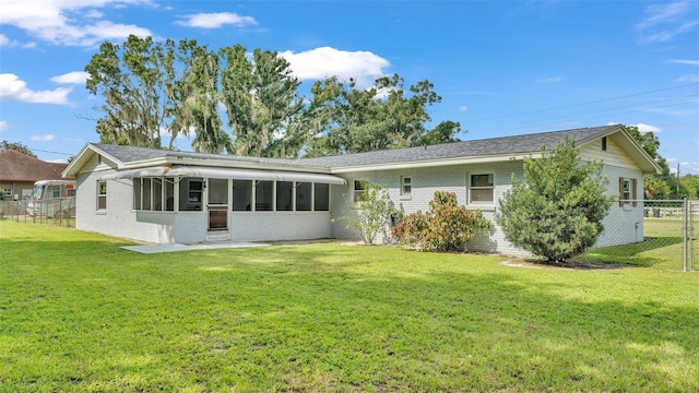 rear view of property featuring a yard and a sunroom