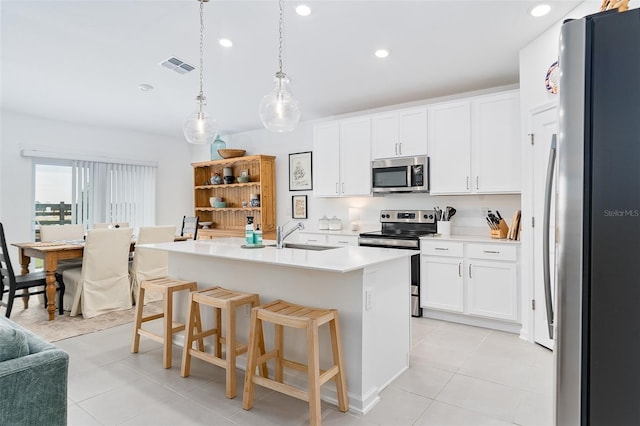 kitchen with hanging light fixtures, white cabinetry, a breakfast bar, a center island with sink, and stainless steel appliances