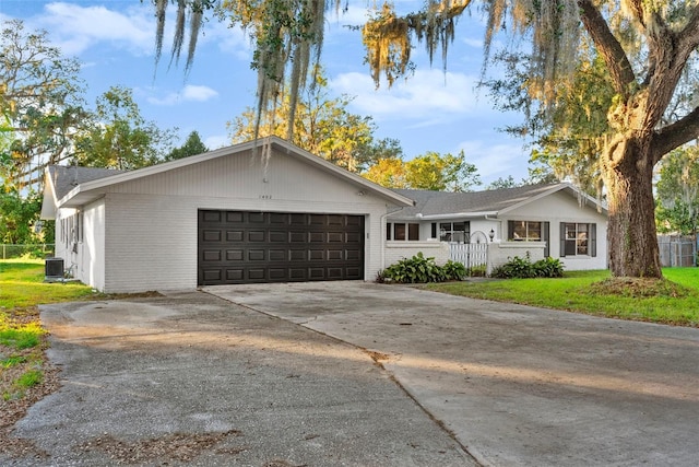 ranch-style house featuring a garage, central air condition unit, and a front yard