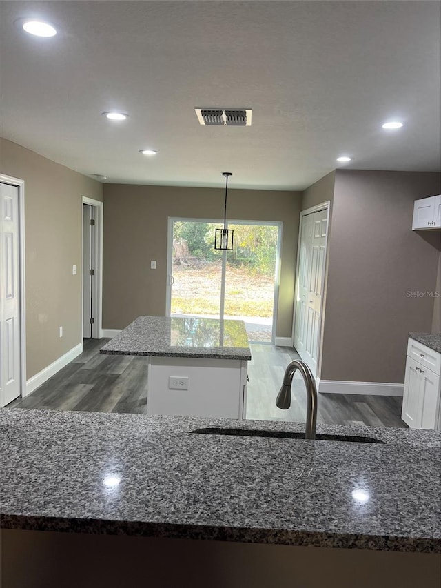 kitchen with white cabinetry, dark stone countertops, hanging light fixtures, and a center island