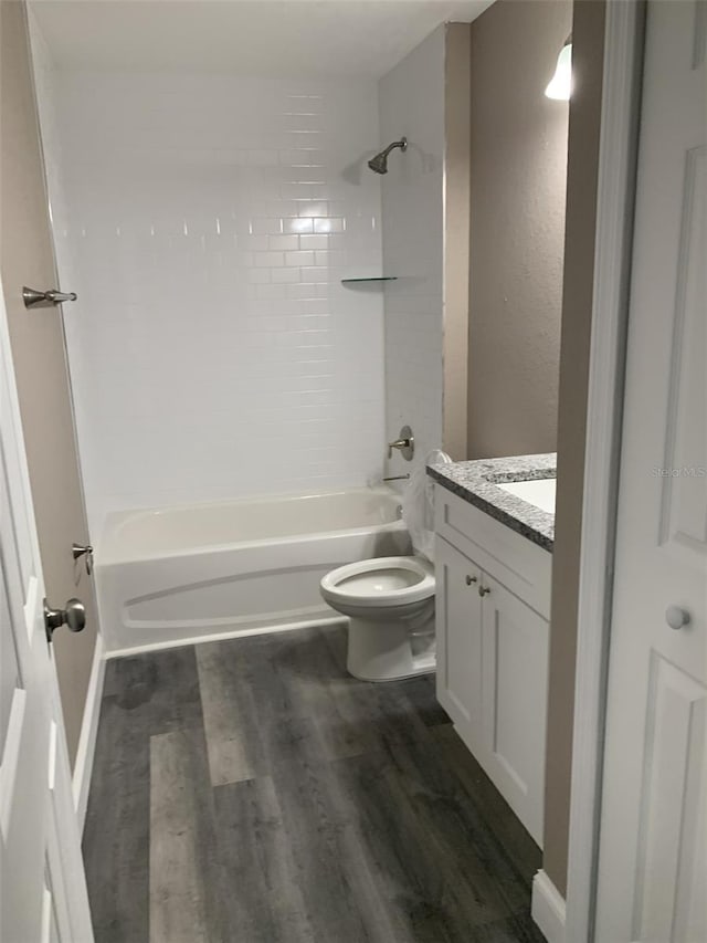 full bathroom with hardwood / wood-style floors, toilet, vanity, and tiled shower / bath