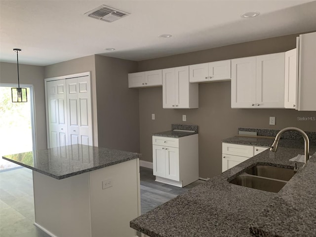 kitchen with sink, white cabinetry, and a kitchen island