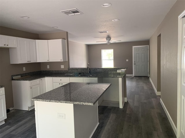 kitchen with ceiling fan, a kitchen island, white cabinets, and sink