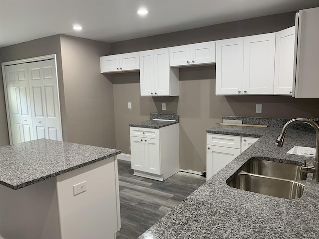 kitchen featuring white cabinetry, dark stone countertops, dark hardwood / wood-style floors, and sink