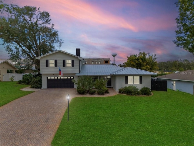 view of front of property with a garage and a lawn