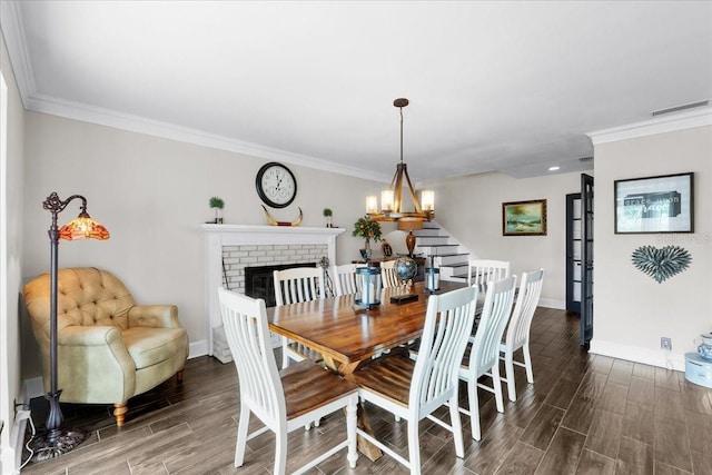 dining space with a fireplace, a chandelier, and crown molding