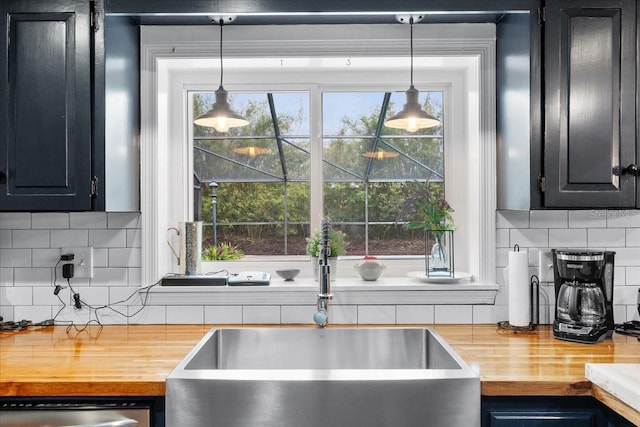 kitchen with wood counters, sink, hanging light fixtures, and tasteful backsplash