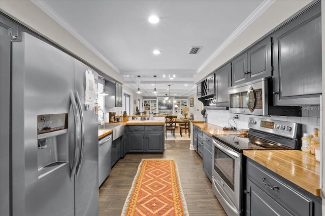 kitchen with wooden counters, ornamental molding, gray cabinetry, stainless steel appliances, and sink