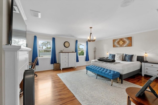 bedroom featuring hardwood / wood-style floors, crown molding, and a chandelier