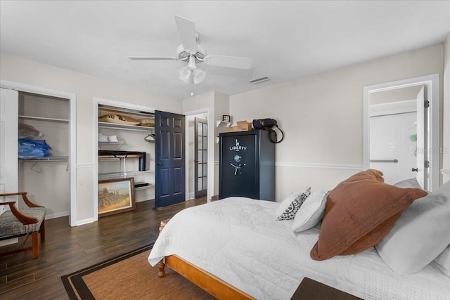 bedroom with dark hardwood / wood-style flooring, ceiling fan, and multiple closets