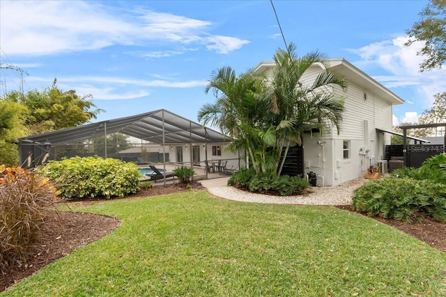 back of property with a yard, a lanai, and central air condition unit