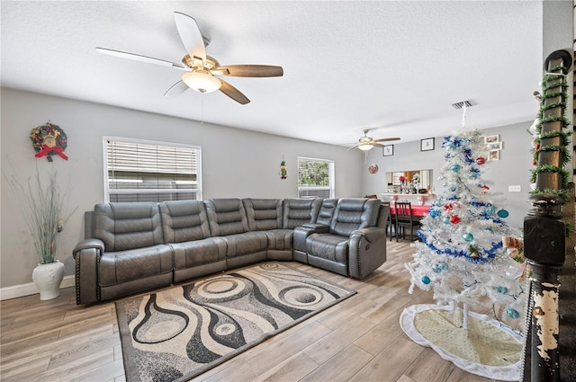 living room featuring a textured ceiling, light hardwood / wood-style floors, and ceiling fan