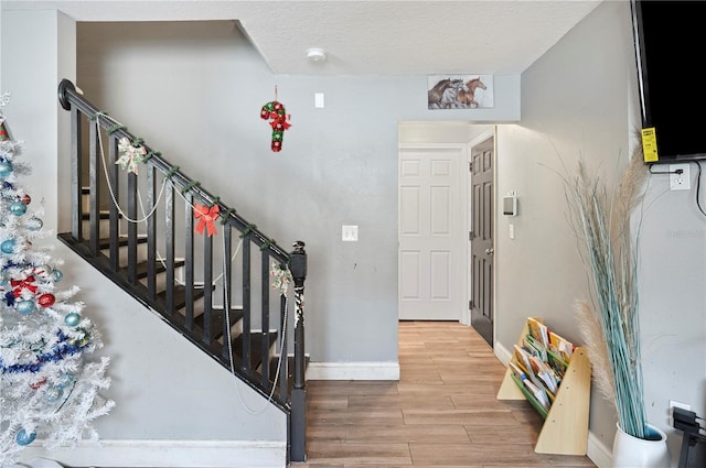 stairs with wood-type flooring and a textured ceiling