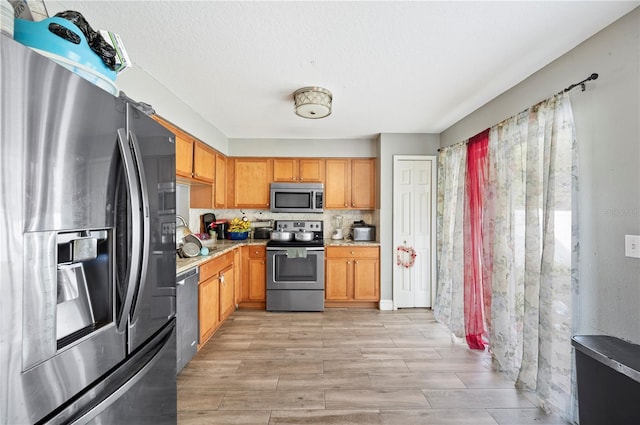 kitchen featuring decorative backsplash, appliances with stainless steel finishes, and light hardwood / wood-style flooring