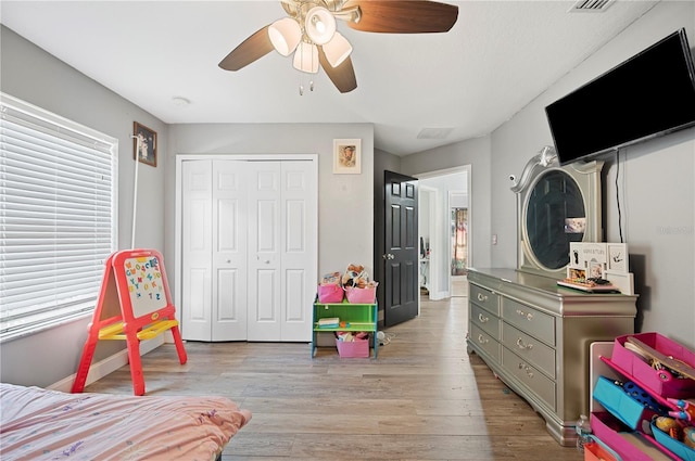 bedroom featuring ceiling fan, light hardwood / wood-style flooring, and a closet