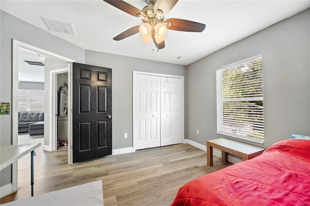 bedroom with a closet, light hardwood / wood-style flooring, and ceiling fan