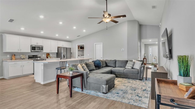 living room with high vaulted ceiling, light hardwood / wood-style floors, and ceiling fan