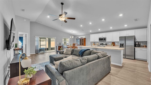 living room featuring high vaulted ceiling, sink, ceiling fan with notable chandelier, and light hardwood / wood-style floors