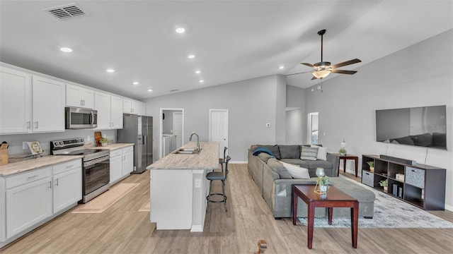 kitchen with sink, a breakfast bar, white cabinets, and stainless steel appliances