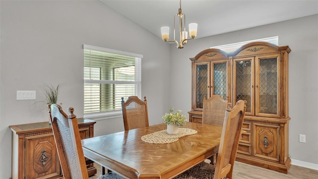 dining space with a chandelier, lofted ceiling, and light hardwood / wood-style flooring