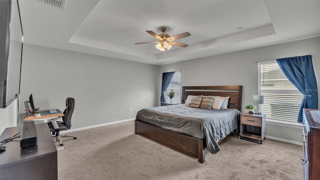 carpeted bedroom with ceiling fan and a raised ceiling