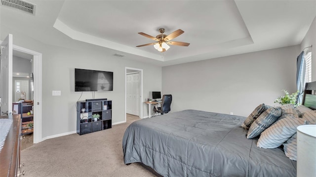 bedroom featuring a raised ceiling, ceiling fan, and carpet